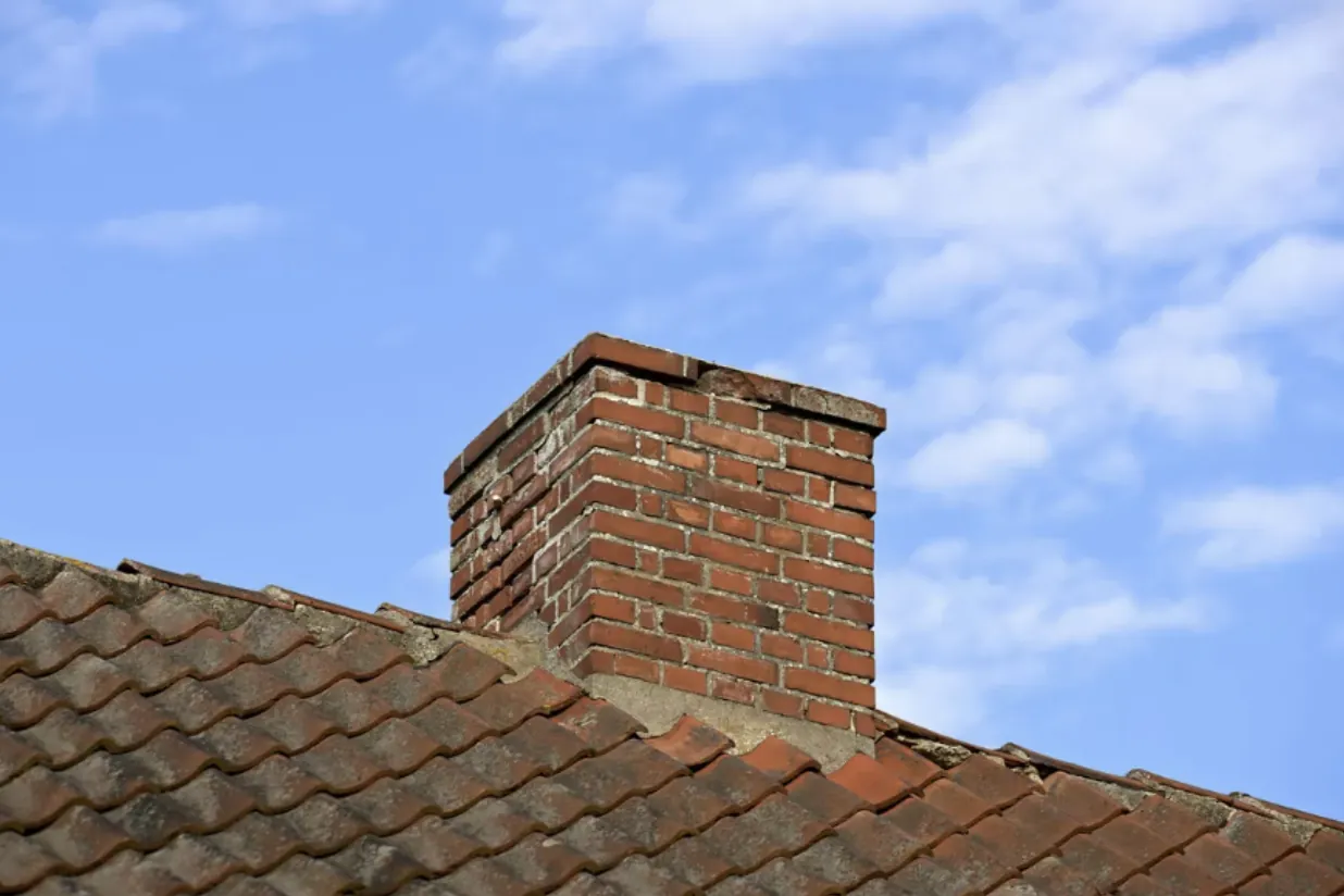 Professional chimney cleaning for a red brick chimney on a residential rooftop in Southern California, highlighting structural maintenance and fire safety.